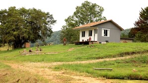 Une maison de plain-pied avec un toit en pente, une véranda avec un banc et un petit jardin.