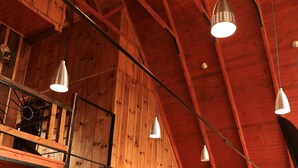 Un intérieur en bois avec un escalier, un coin repas et des suspensions décoratives.