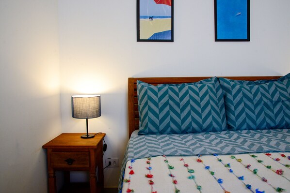 A bedroom with a bed, a nightstand with a lamp, and two framed pictures on the wall.
