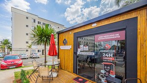 A compact store with a wooden exterior, a glass door, and a sign indicating 24-hour operation. - Confort vel Apartamento com Wi-fi pet Friendly (Sorocaba)