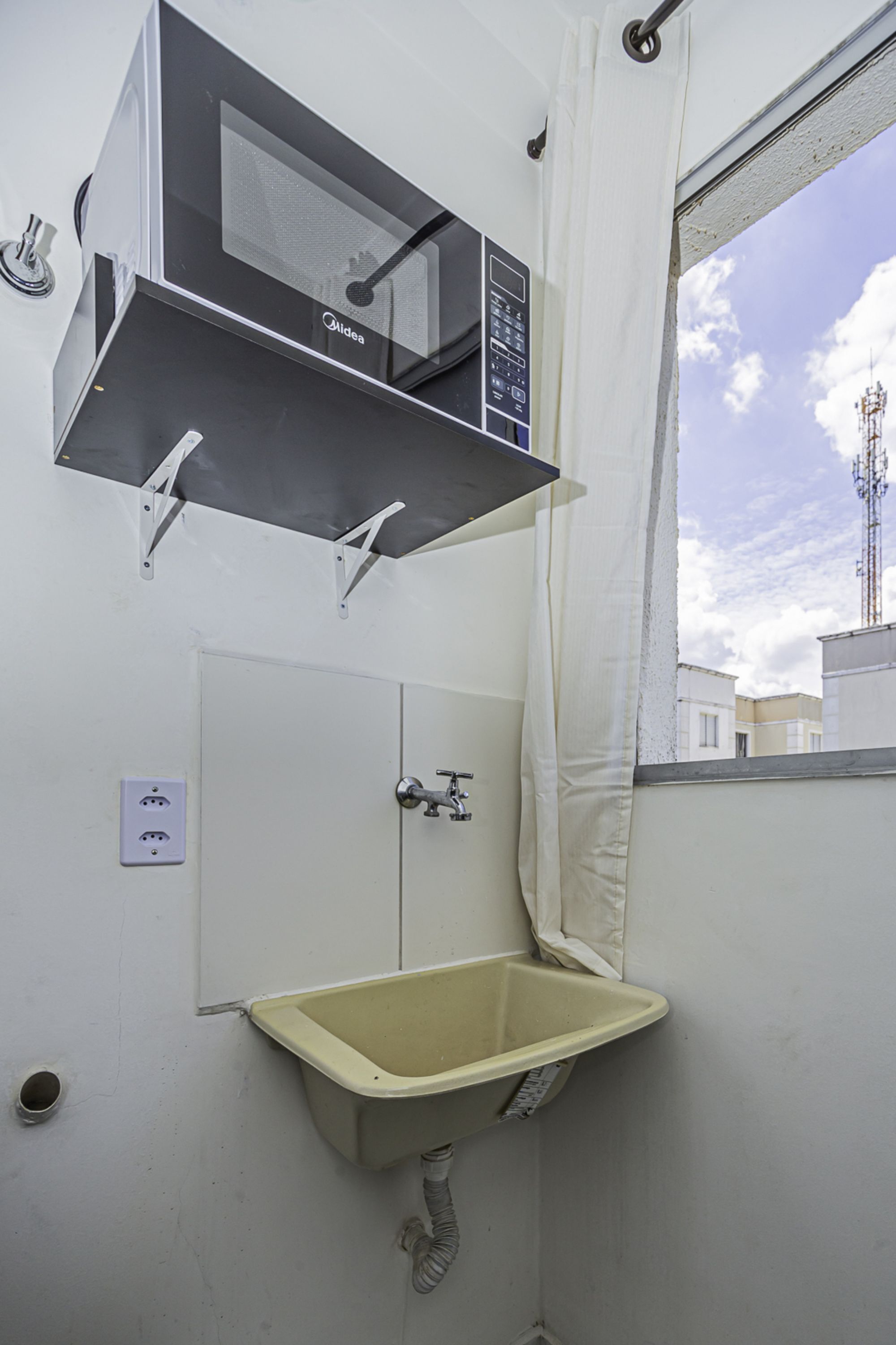 Un baño con ventana, lavamanos y cabina de ducha.