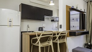 A modern kitchen with a built-in refrigerator, wooden bar stools, and pendant lighting. - Confort vel Apartamento com Wi-fi pet Friendly (Sorocaba)