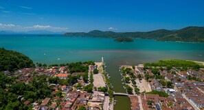 An aerial view of a coastal town with a marina, residential buildings, and a lighthouse.