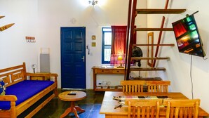 Une pièce chaleureuse avec une porte bleue, des meubles en bois, une petite table et un téléviseur fixé au mur.
