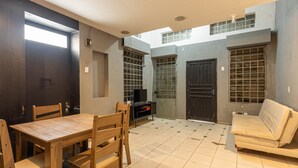 A room with a wooden table and chairs, a sofa, and a TV on a stand. - Casa Triplex com Tima Localiza o Pet Friendly (Porto Alegre)