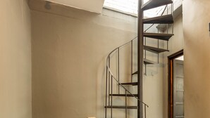 A spiral staircase in a room with plain walls and a tiled floor. - Casa Triplex com Tima Localiza o Pet Friendly (Porto Alegre)