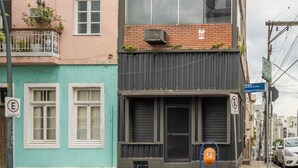 A multi-story building with a mix of architectural styles, including a pink facade with ornate details, a teal-colored section with a balcony, and a modern black section with large windows. - Casa Triplex com Tima Localiza o Pet Friendly (Porto Alegre)