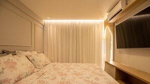 A bedroom with a bed, a TV, and a window with curtains. - Apto Confort vel com Wi-fi e Churrasqueira (Fortaleza)