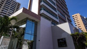 A tall, modern hotel with a prominent glass facade and a clear view of the sky. - Apto Confort vel com Wi-fi e Churrasqueira (Fortaleza)