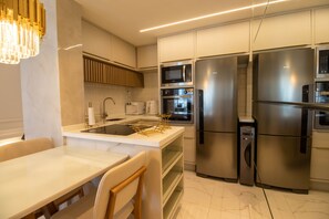 Una cocina moderna con electrodomésticos de acero inoxidable, una encimera blanca y una zona de comedor con mesa y sillas.