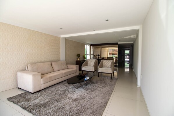 Un salon moderne avec un canapé beige, deux fauteuils, une table basse et un tapis.
