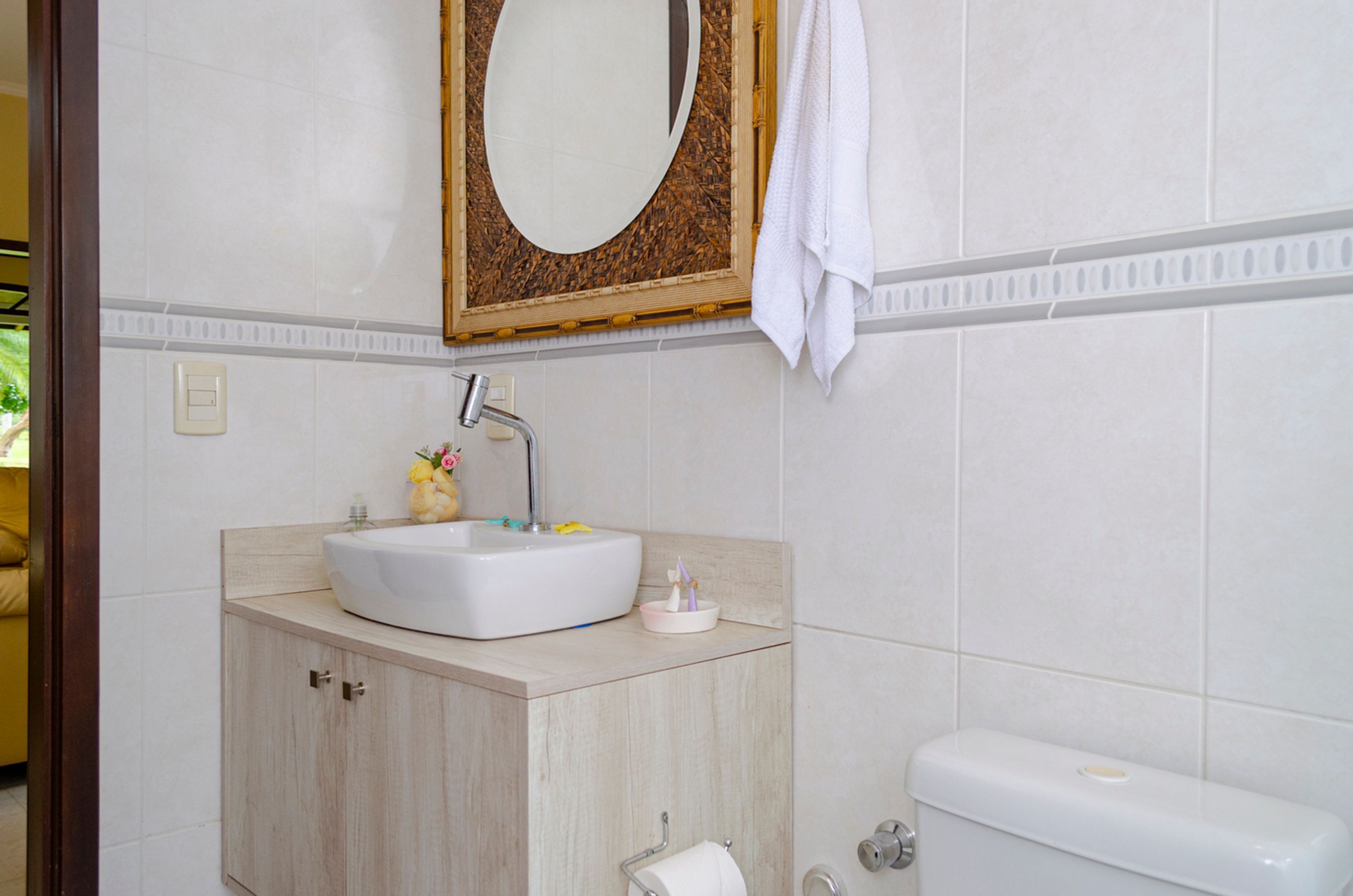 Een badkamer met een wit wastafel, een spiegel, een toilet en een handdoek aan de muur.