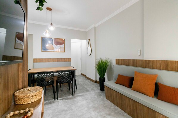 Un intérieur moderne comprenant un coin repas, un canapé avec des coussins, un miroir et un luminaire suspendu.