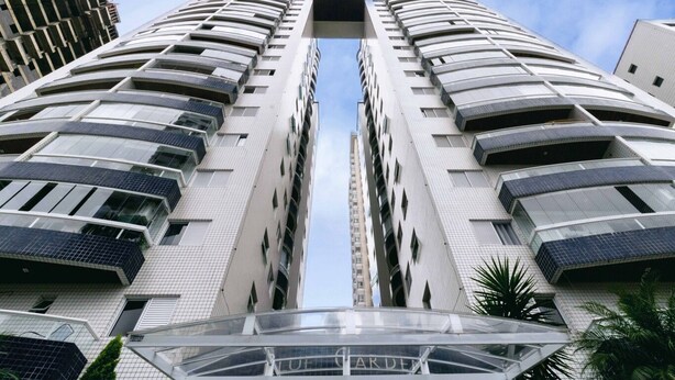 A high-rise building with a central atrium and multiple balconies. - Apto a 500m da Praia Canto do Forte - Praia Grande (Praia Grande)