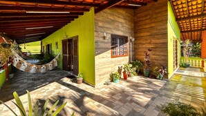 A spacious outdoor area with a hammock, potted plants, and a tiled floor. - Ch Cara Iracema com Lazer Completo e Wi-fi (Salto)