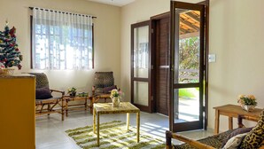 A cozy living room with a Christmas tree, two chairs, a table, and a large sliding glass door leading to an outdoor area. - Ch Cara Iracema com Lazer Completo e Wi-fi (Salto)