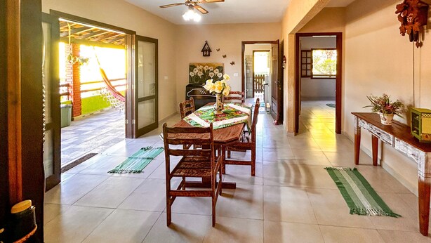 A dining area with a table set for four, a ceiling fan, and a view of the outside. - Ch Cara Iracema com Lazer Completo e Wi-fi (Salto)