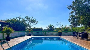 A rectangular swimming pool with a tiled deck, surrounded by a white fence and potted plants. - Ch Cara Iracema com Lazer Completo e Wi-fi (Salto)