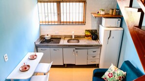A compact kitchen with a window, sink, microwave, and a small dining area. - Chal com Piscina e Churrasq em Caraguatatuba SP (Caraguatatuba)
