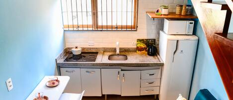 A compact kitchen with a window, sink, microwave, and a small dining area.