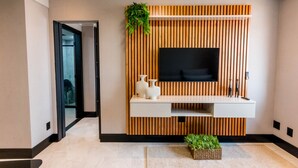 A modern lobby with a wooden panel wall, a mounted TV, and a reception desk. - Flat Equipado em Tima Localiza o Wi-fi e Lazer (Barueri)