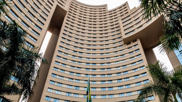 Un bâtiment d’hôtel à la forme incurvée, doté de plusieurs étages, d’une entrée centrale et de plusieurs drapeaux.
