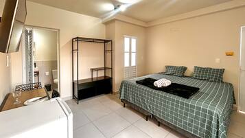 Un dormitorio con cama, armario, escritorio y espejo.