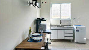 A compact kitchen with a microwave, refrigerator, and a window providing natural light. - Loft p Home Office com Wifi em Sorocaba SP (Sorocaba)