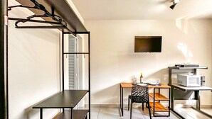 A compact kitchen with a dining table, chairs, a microwave, and a TV mounted on the wall. - Loft p Home Office com Wifi em Sorocaba SP (Sorocaba)