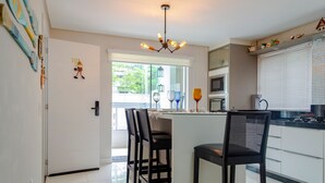 A modern kitchen with a central island, black chairs, and a dining area. - Apto pr Ximo do mar e do Beto Carrero World (Penha)