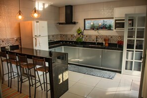 Una cocina moderna con una isla central, taburetes de bar e iluminación colgante.