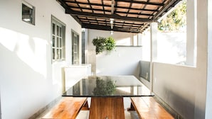 A patio with a glass-top table and wooden benches. - Casa c Tima Localiza o em Teixeira de Freitas-ba (Teixeira de Freitas)