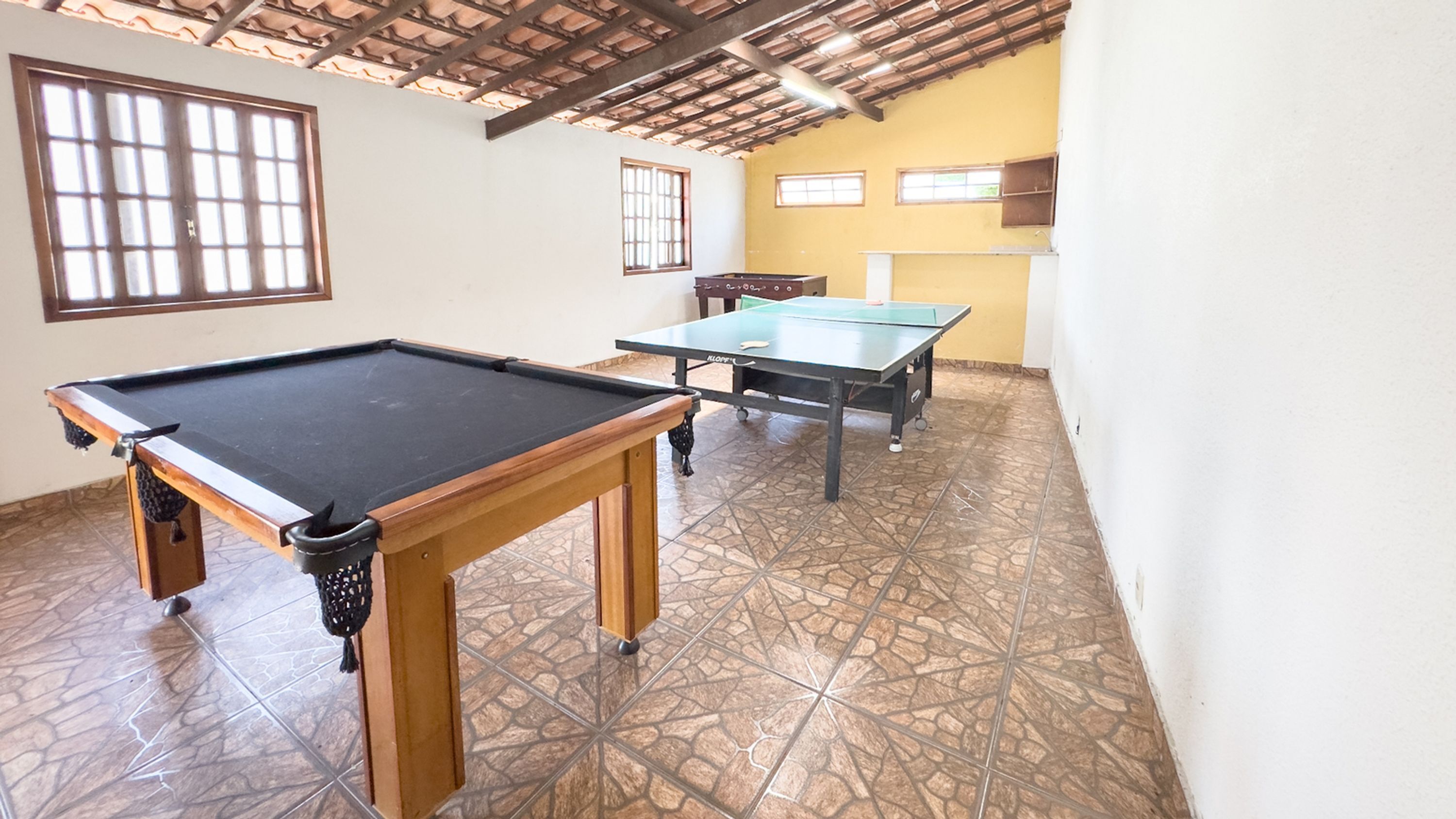 Una habitación con mesa de billar, mesa de ping pong y mesa de futbolín.