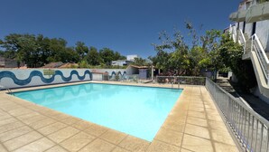 A swimming pool with tiled edges, surrounded by a fence and a tiled deck. - Aconchegante e Espa oso Apto c Piscina e Churrasq (Cabo Frio)