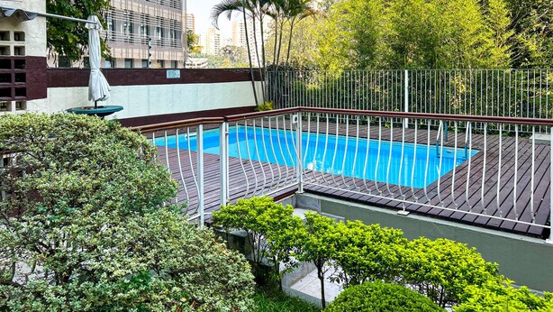 A rooftop pool with a wooden deck, surrounded by a metal fence and lush greenery. - Apto Espa oso c Wifi pr x a Marginal Pinheiros SP (São Paulo)