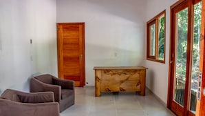 A room with a wooden door, a wooden bench, and two brown chairs. - Suite Recanto dos Macacos - Quarto 2 (Prado)