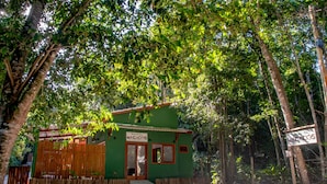 A small, green building with a sign reading "MACACOS" and a wooden fence in front. - Suite Recanto dos Macacos - Quarto 2 (Prado)