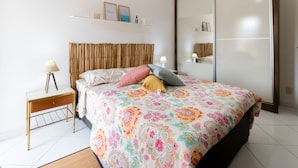 A bedroom with a bed, bedside table, lamp, and a wardrobe. - Timo Apto c Wifi a 700m da Praia do Tombo-guaruj (Guarujá)