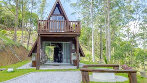 A wooden cabin with a balcony, surrounded by trees and a grassy area. - Charmoso Chal no Campo com Vista Para a Natureza (Sao Pedro de Alcantara)