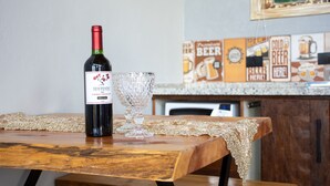 A bottle of wine and a glass on a wooden table with a lace tablecloth. - Cabana com Jacuzzi e Churrasqueira - Ibi na SP (Ibiuna)