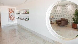 Un interior moderno con un espejo circular, un sillón de cuero marrón y una pared decorativa con estanterías.