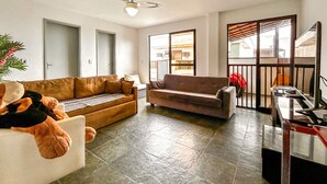 A living room with two sofas, a ceiling fan, and a view through a glass door to the outside. - Incr vel Apto a 800m da Praia do Forte - Cabo Frio (Cabo Frio)