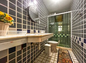 Une salle de bain avec un mur carrelé, un lavabo, des toilettes et un espace douche.