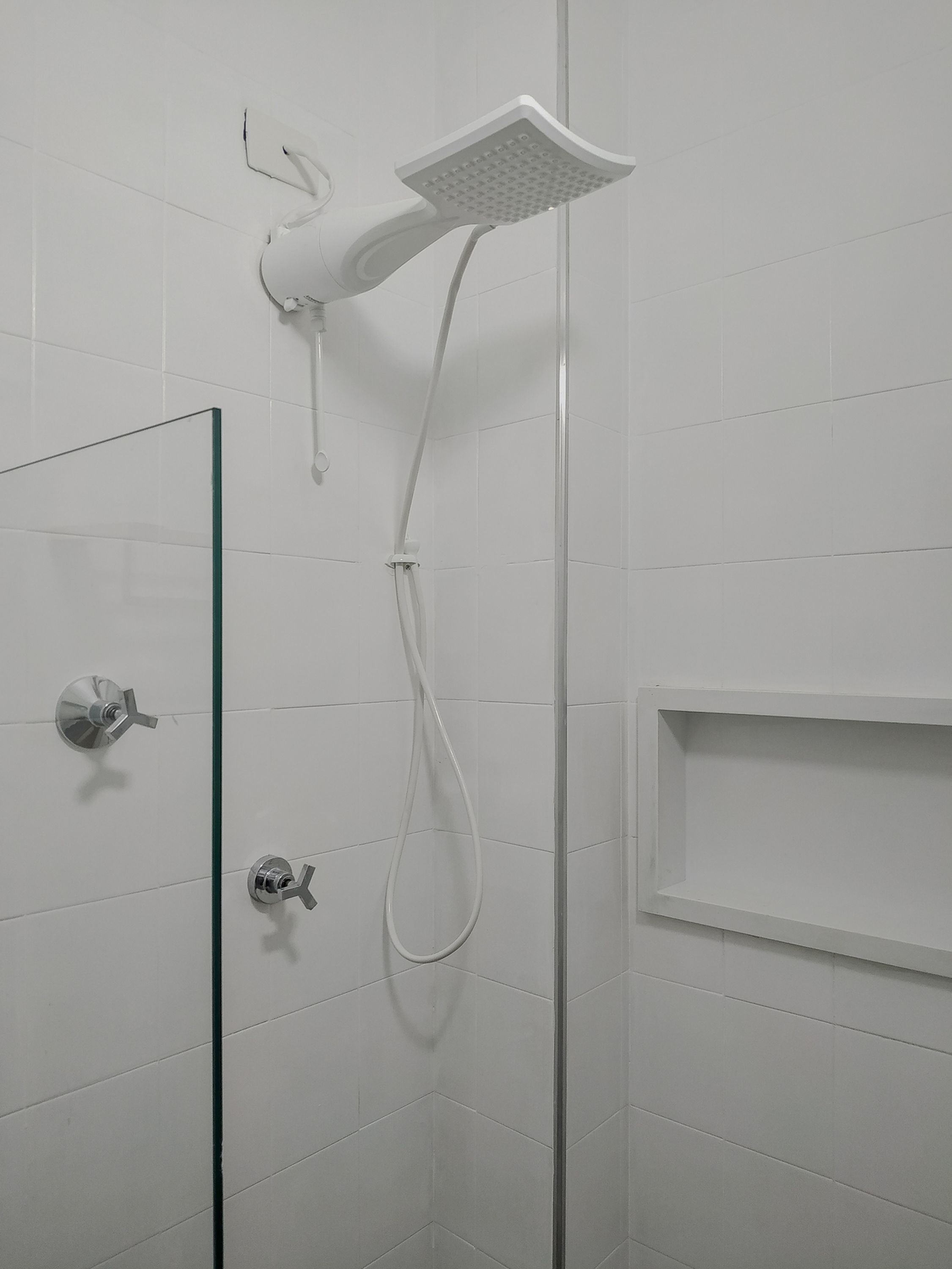 A modern shower with a handheld showerhead and a wall-mounted control.