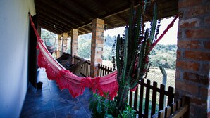 A covered porch with a hammock, brick pillars, and a view of the countryside.