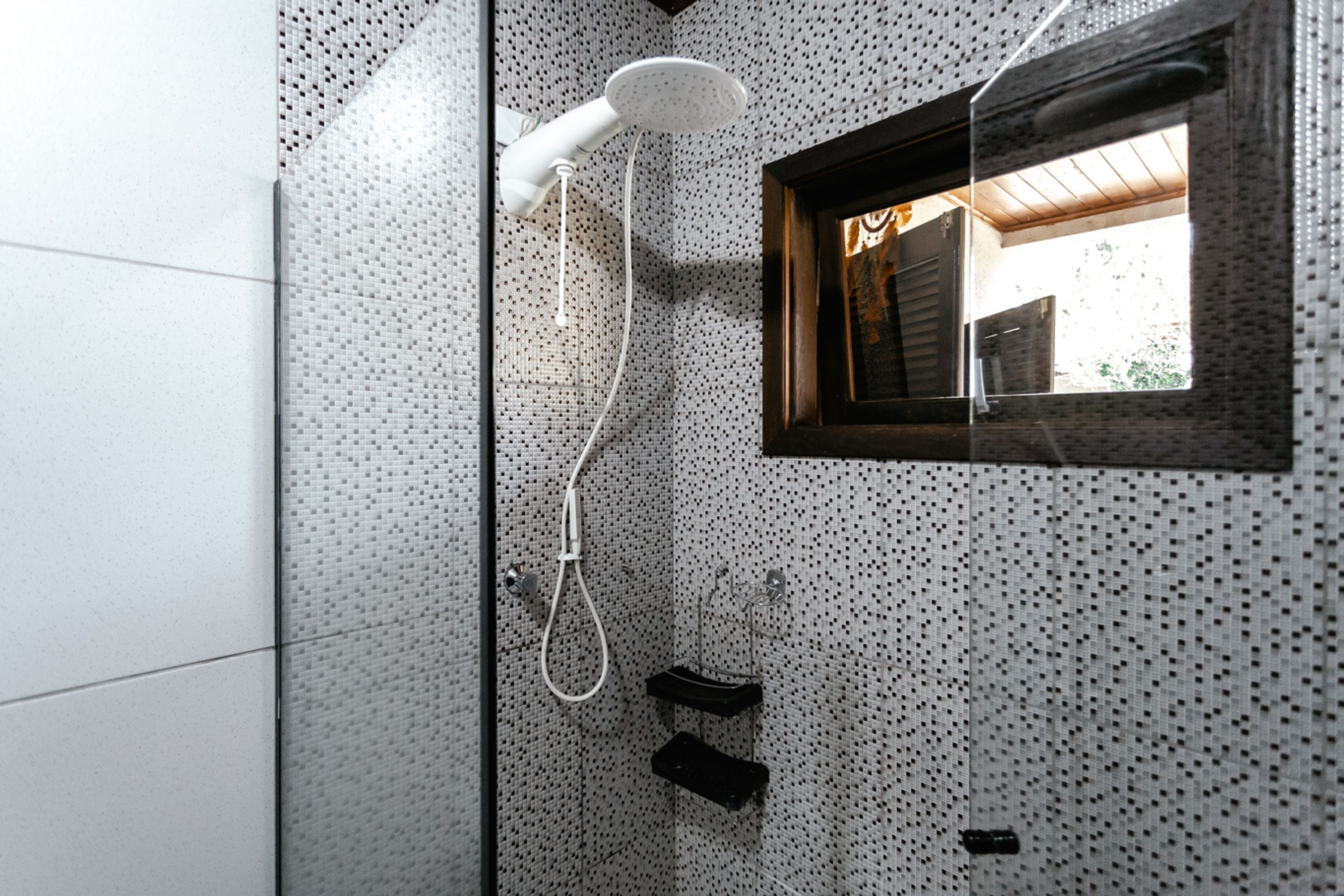 A bathroom with a shower, a small window, and tiled walls.