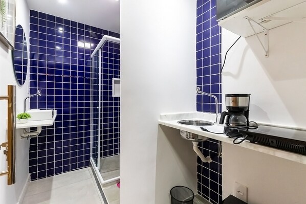A modern bathroom with blue tiles, a white sink, and a coffee maker on the countertop. - Loft pr x do Aeroporto no Centro e com Wi-fi (Rio de Janeiro)