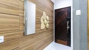 A hallway with wooden paneling, a white door with a textured design, and a wall-mounted decorative piece. - Loft pr x do Aeroporto no Centro e com Wi-fi (Rio de Janeiro)