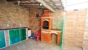 A kitchen with a brick oven, stone walls, and a green countertop. - Casa Beira-mar com Piscina em Saquarema RJ (Saquarema)