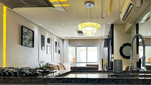 A modern kitchen with a central island, pendant lighting, and a view to the living area. - Timo Apto de Frente Para Praia do Boqueir o SP (Praia Grande)